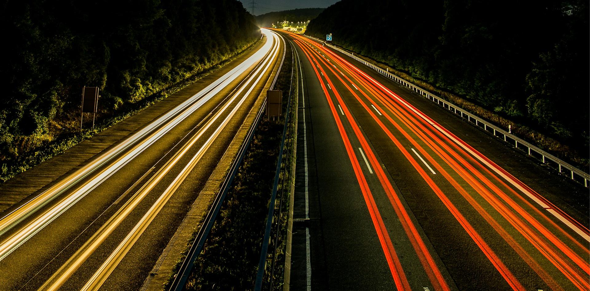 Langzeitbelichtung einer Autobahn bei Nacht mit durchgehenden Lichtspuren der Fahrzeuge