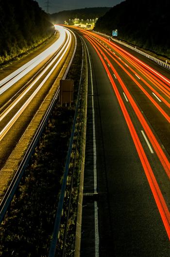 Langzeitbelichtung einer Autobahn bei Nacht mit durchgehenden Lichtspuren der Fahrzeuge